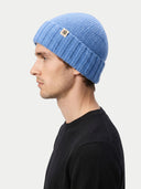 side view of a man wearing a blue knit beanie on a white background.