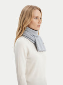 Woman wearing a light gray scarf on a white background.
