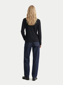 back view of a woman wearing a black cashmere long sleeve shirt and blue jeans on a white background.