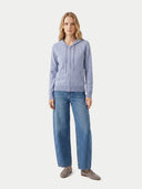 Woman wearing a light blue hoodie and jeans on a white background.