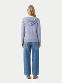 back view of a person wearing a light purple hoodie and blue jeans on a white background.