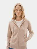 Woman wearing a beige hoodie on a plain background