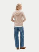 Person wearing a beige hoodie and blue jeans on a white background