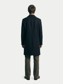 Person wearing a black coat from behind on a white background
