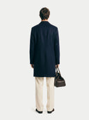 Navy knit vest over a white long-sleeve shirt on a white background