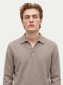 A man wearing a light brown knit polo sweater, photographed from the chest up against a plain light gray background.