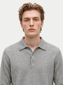 A man wearing a light gray long-sleeve knit polo shirt, shown from the chest up against a plain light gray background.