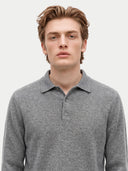 A man wearing a gray long-sleeve polo shirt, photographed from the chest up against a plain light gray background.