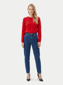 A woman modeling a bright red long-sleeve knit sweater and dark blue high-waisted straight-leg jeans with black pointed-toe heels, shot against a light gray studio background.