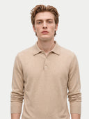 A man wearing a beige long-sleeve knit polo shirt, photographed against a clean light gray studio background.