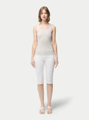 A woman wearing a beige lightweight cashmere silk tank top with no visible pattern or print, paired with white trousers. #color_pure-white