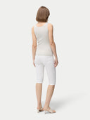 A woman wearing a beige lightweight cashmere silk tank top with no visible pattern or print, paired with white trousers. #color_pure-white