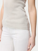 A woman wearing a beige lightweight cashmere silk tank top with no visible pattern or print, paired with white trousers. #color_pure-white
