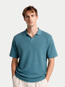 Man wearing a teal polo shirt against a white background.