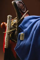A blue GOBI cashmere sweater draped over an ornate carved wooden saddle