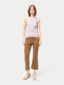 A woman wearing a ribbed cotton silk cashmere blend tank top in primrose pink color, paired with brown trousers. #color_wind-chime