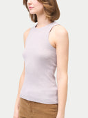 A woman wearing a ribbed cotton silk cashmere blend tank top in primrose pink color, paired with brown trousers. #color_wind-chime
