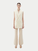 Woman wearing a white sleeveless cashmere blazer on a plain background #color_off-white