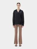 A woman wearing a black cashmere wrap shirt with a V-neck and single-button closure. #color_black