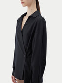 A woman wearing a black cashmere wrap shirt with a V-neck and single-button closure. #color_black