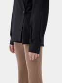A woman wearing a black cashmere wrap shirt with a V-neck and single-button closure. #color_black