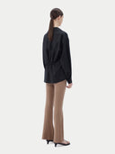 A woman wearing a black cashmere wrap shirt with a V-neck and single-button closure. #color_black