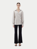 Woman wearing a light gray cashmere blouse with a plain background. #color_wind-chime