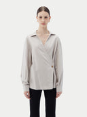 Woman wearing a light gray cashmere blouse with a plain background. #color_wind-chime