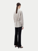 Woman wearing a light gray cashmere blouse with a plain background. #color_wind-chime