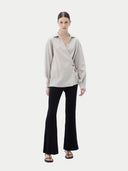 Woman wearing a light gray cashmere blouse with a plain background. #color_wind-chime