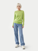 Person wearing a green sweater and blue jeans on a white background. #color_jade-green