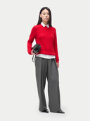 A woman wearing a red cashmere crew neck sweater with a white collar and gray pants. #color_true-red
