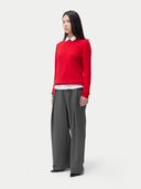 A woman wearing a red cashmere crew neck sweater with a white collar and gray pants. #color_true-red