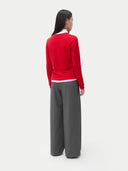 A woman wearing a red cashmere crew neck sweater with a white collar and gray pants. #color_true-red