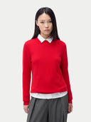 A woman wearing a red cashmere crew neck sweater with a white collar and gray pants. #color_true-red