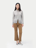 A woman standing and facing the camera, wearing a full-zip cardigan in a light color with side pockets, paired with brown trousers. #color_steel-silver