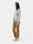 A woman standing and facing the camera, wearing a full-zip cardigan in a light color with side pockets, paired with brown trousers. #color_steel-silver