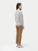 A woman standing and facing the camera, wearing a full-zip cardigan in a light color with side pockets, paired with brown trousers. #color_steel-silver