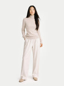 A light beige knit cashmere turtleneck sweater with long sleeves and ribbed cuffs and hem, displayed against a clean white background. #color_soft-beige