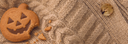 Pumpkin-shaped biscuit with a bite taken out, on a beige cable-knit GOBI cashmere cardigan
