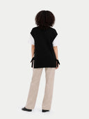 back view of a black sleeveless top and beige pants on a white background