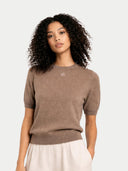 Woman wearing a brown sweater against a plain background