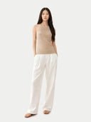 Woman wearing a beige sleeveless cashmere top against a white background. #color_warm-grey