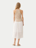 Woman wearing a beige sleeveless cashmere top against a light background. #color_beige