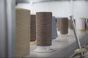 Cones of grey and cream cashmere yarn on a knitting machine in GOBI's knitting factory