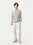 Person wearing a gray long-sleeve shirt and white pants on a white background. #color_urban-gray