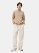Man wearing a beige turtleneck cashmere sweater against a white background. #color_soft-beige