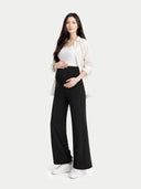 Woman wearing a white shirt, black maternity pants, and white sneakers on a white background