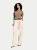 Woman wearing a brown top and beige pants on a white background