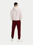 A pair of dark burgundy cashmere jogger sweatpants with an elastic waistband, drawstring, and side pockets, shown flat against a light gray background. #color_dusty-plum